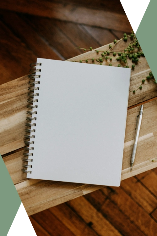 photo of a blank notebook on a wooden bench next to a pen and a string of pearls plant ("About Us" section image on "About Caesura Strategy" page)